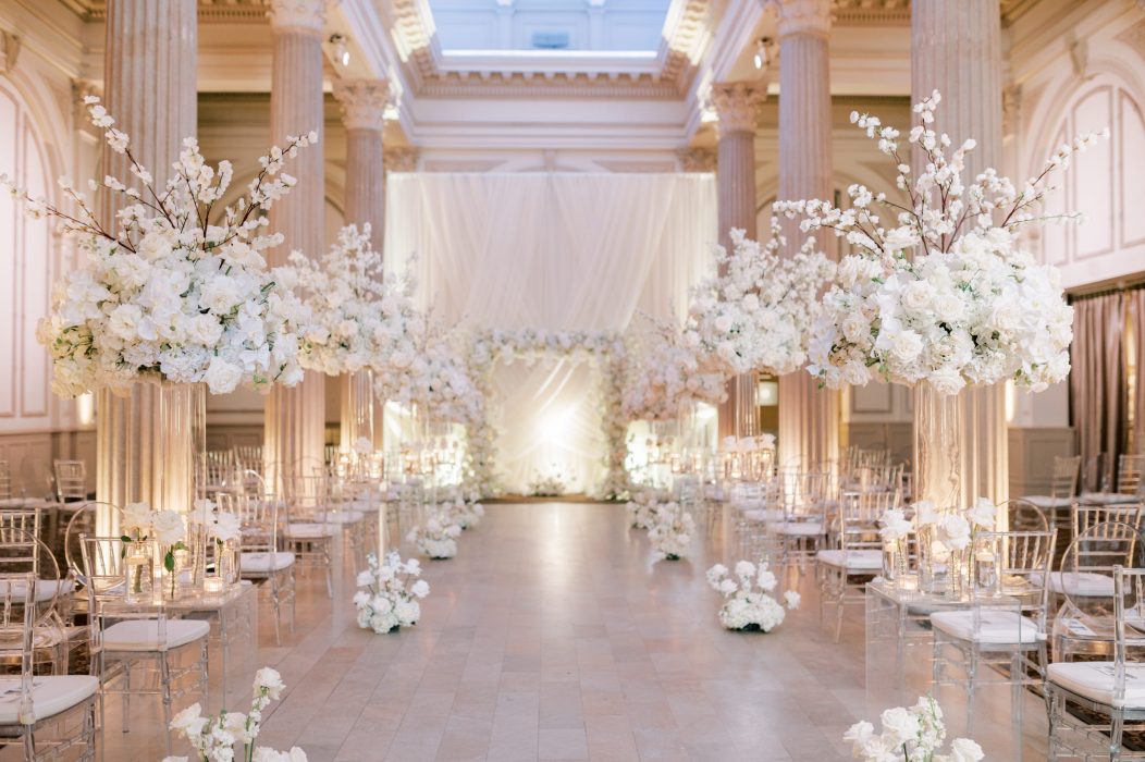 Tall white floral arrangements for a wedding ceremony.