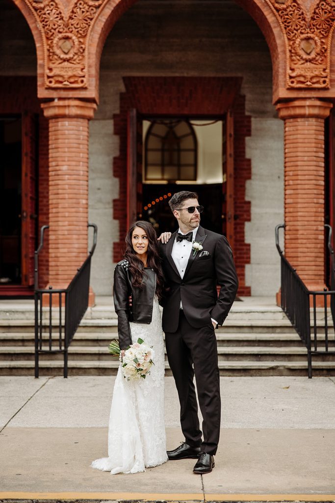 Bride in a leather jacket over her wedding dress for a modern wedding day look