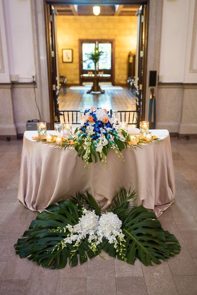 Palm leaves and flowers that decorated the altar during the wedding ceremony are used at the sweetheart’s table during the reception.
