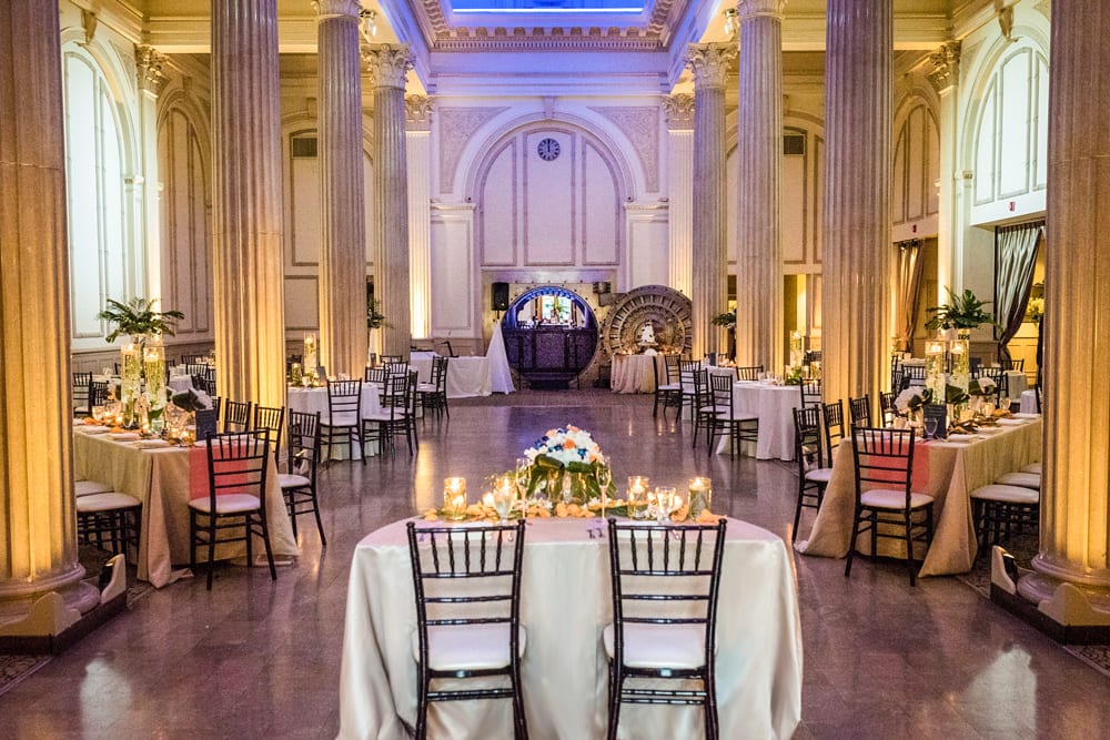The sweetheart table sits at the front of the ballroom for the reception with tables set up along the sides of the room.