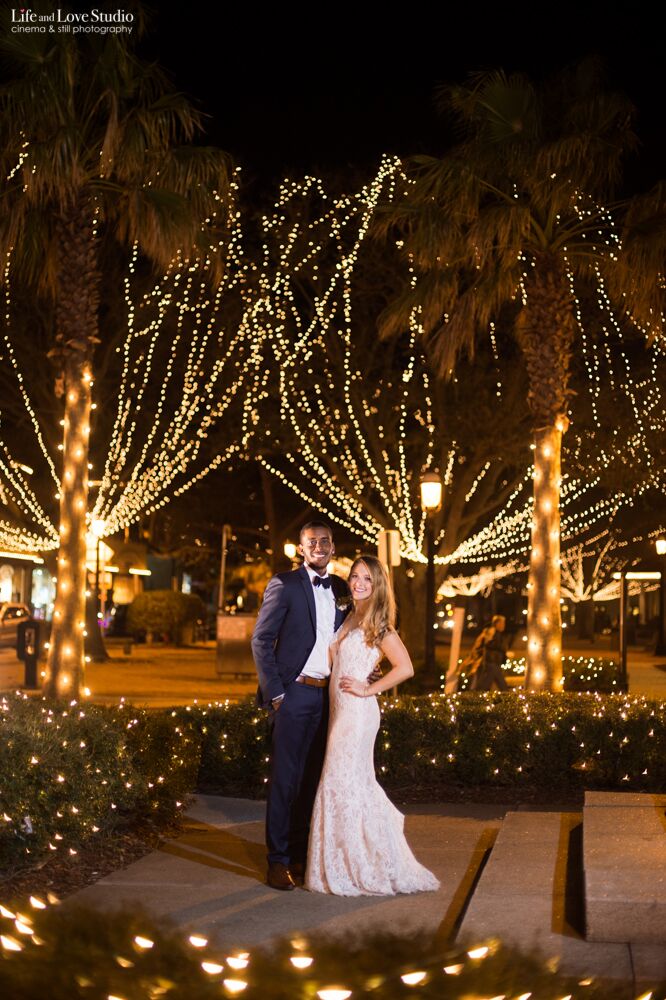 bride and groom in front of trees lit with holiday lights