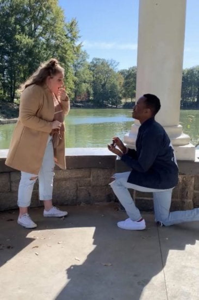 A man proposes to his girlfriend in front of a pond.