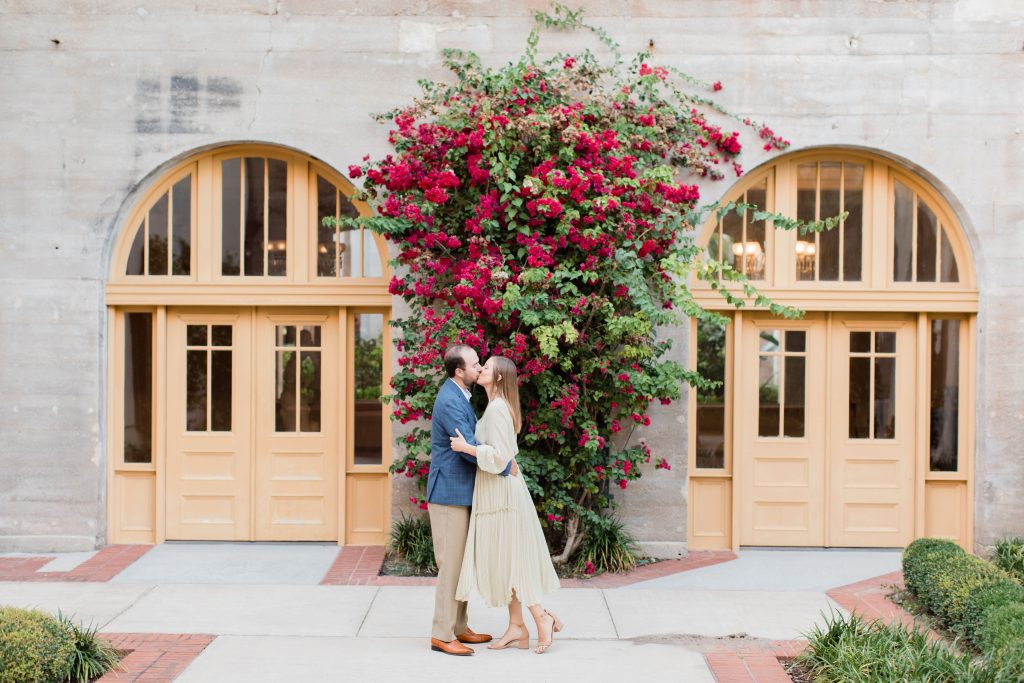engaged couple kissing in front of bougainvilla plant at the Lightner Museum in St. Augustine