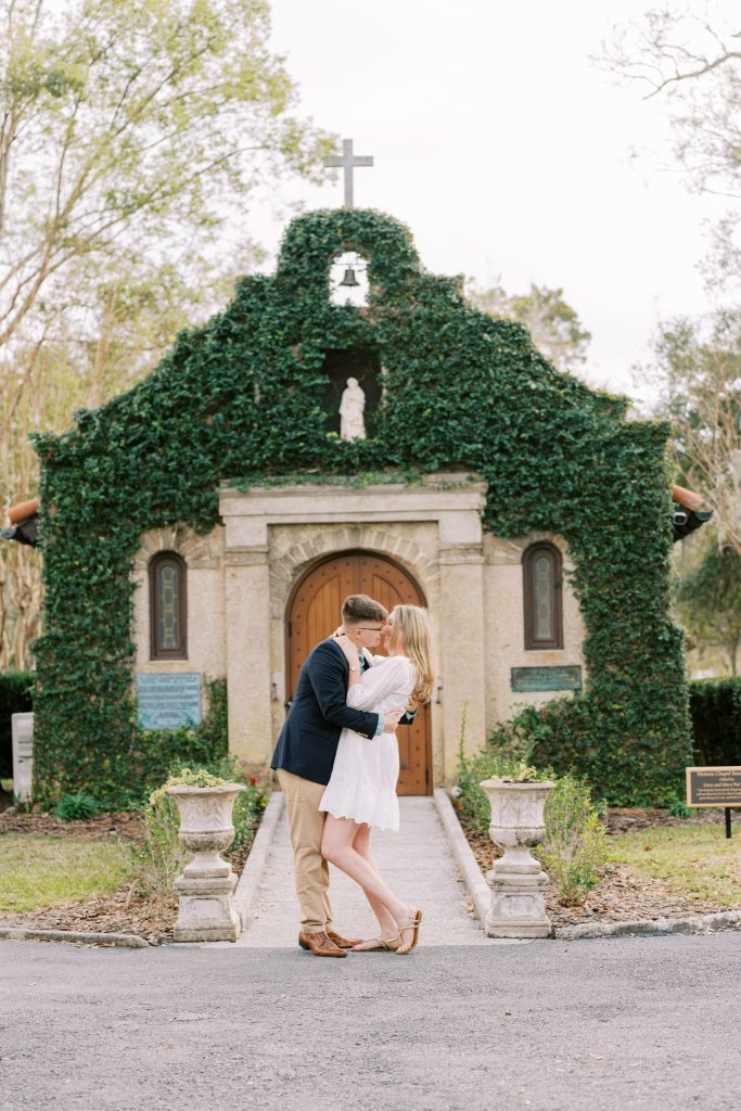 engaged couple kiss in front of historic building covered in ivy