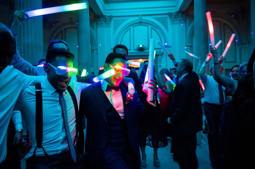 wedding guests in dark reception hall with glow in the dark glasses and wands