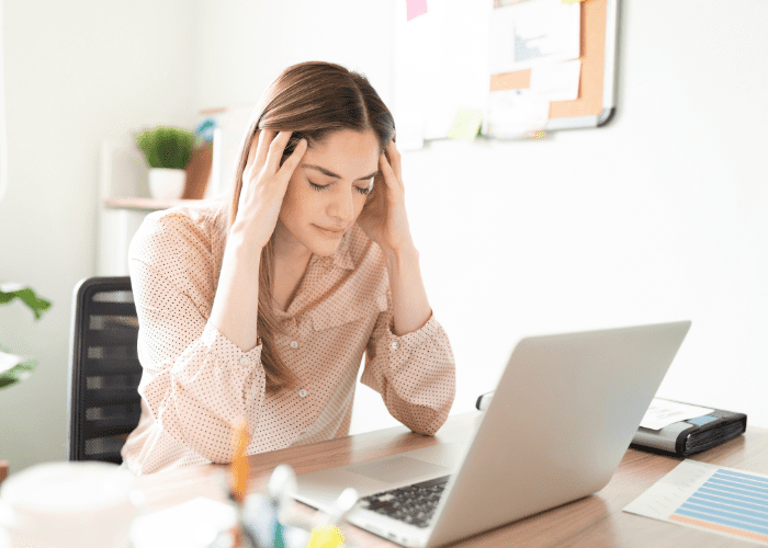 woman in front of laptop with hands on her head