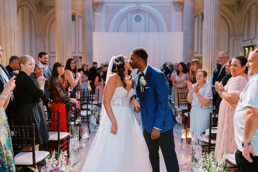 Sarah and Kevin kissing as they walk down the aisle