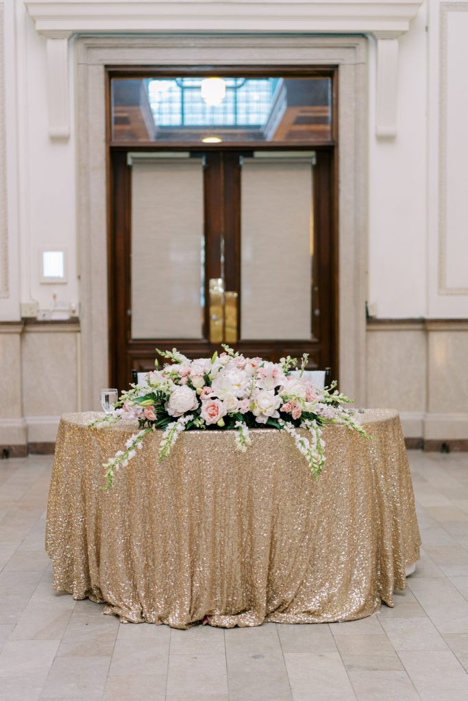 floral arrangement on sweetheart table with glittery gold linen