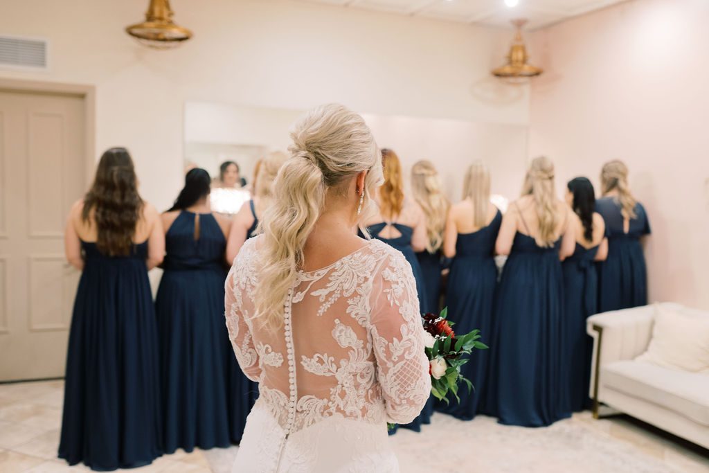 Jess standing behind bridesmaids, all of them turned away from her