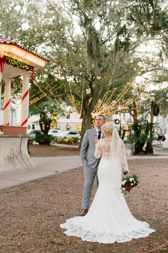 bride and groom in park lit with christmas lights