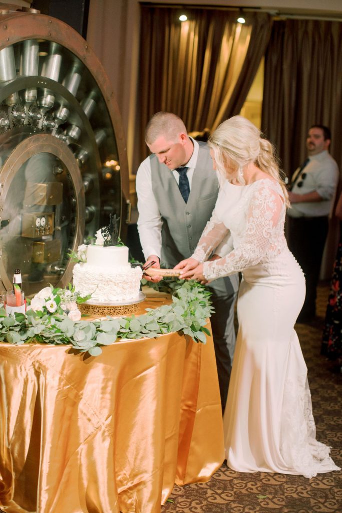Matt and Jess cutting their wedding cake with a custom hatchet