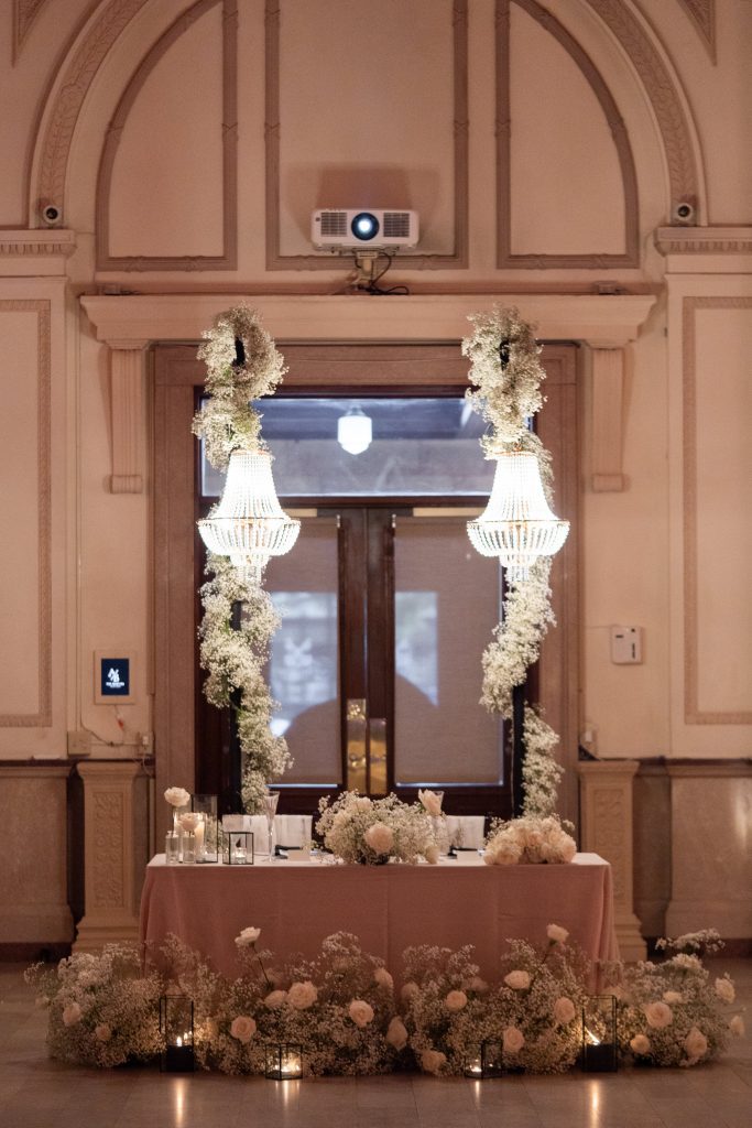 crystal chandeliers hanging from posts at sweetheart table