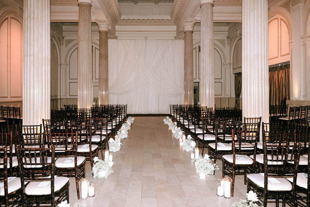 Wedding aisle lined with candles and sprays of baby's breath