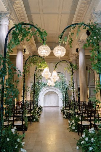 wedding aisle lined with greenery-wrapped chandeliers