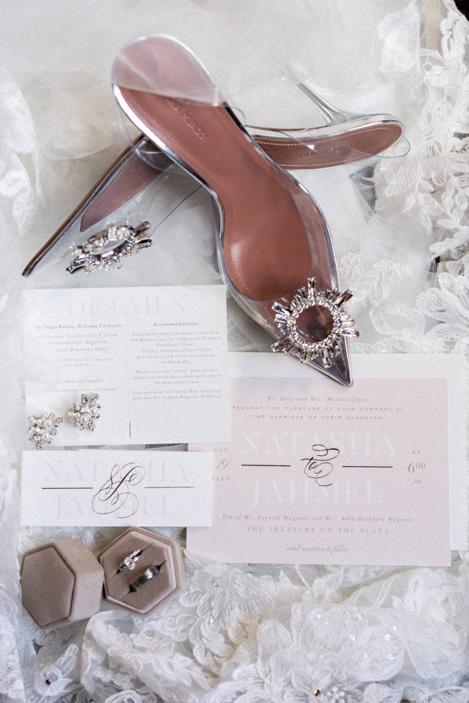 Flat lay of bride's shoes, wedding invitations, and wedding rings