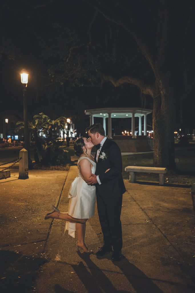 Nighttime shot of bride and groom kissing after wedding reception