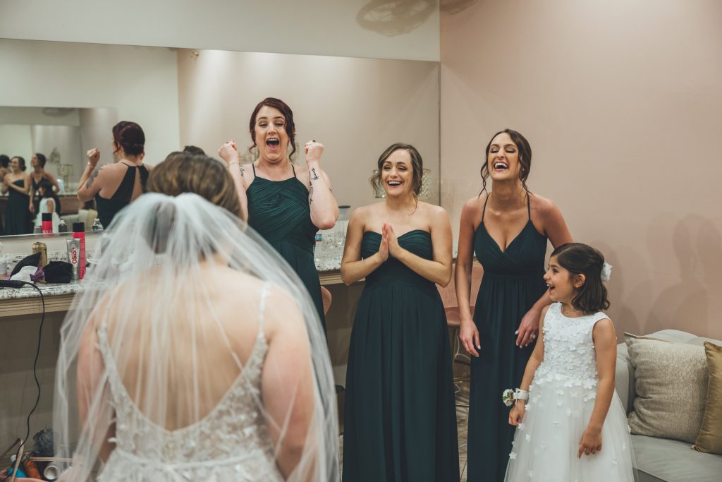 three bridesmaids and flower girl exclaiming over seeing bride for the first time