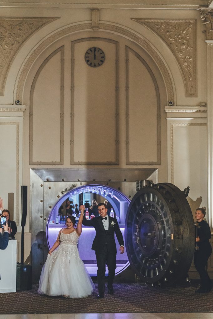bride and groom entering the wedding reception through vault door