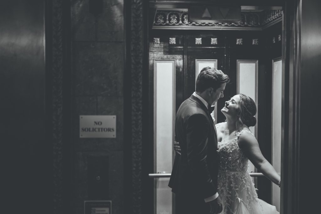 black and white photo of bride and groom in antique elevator
