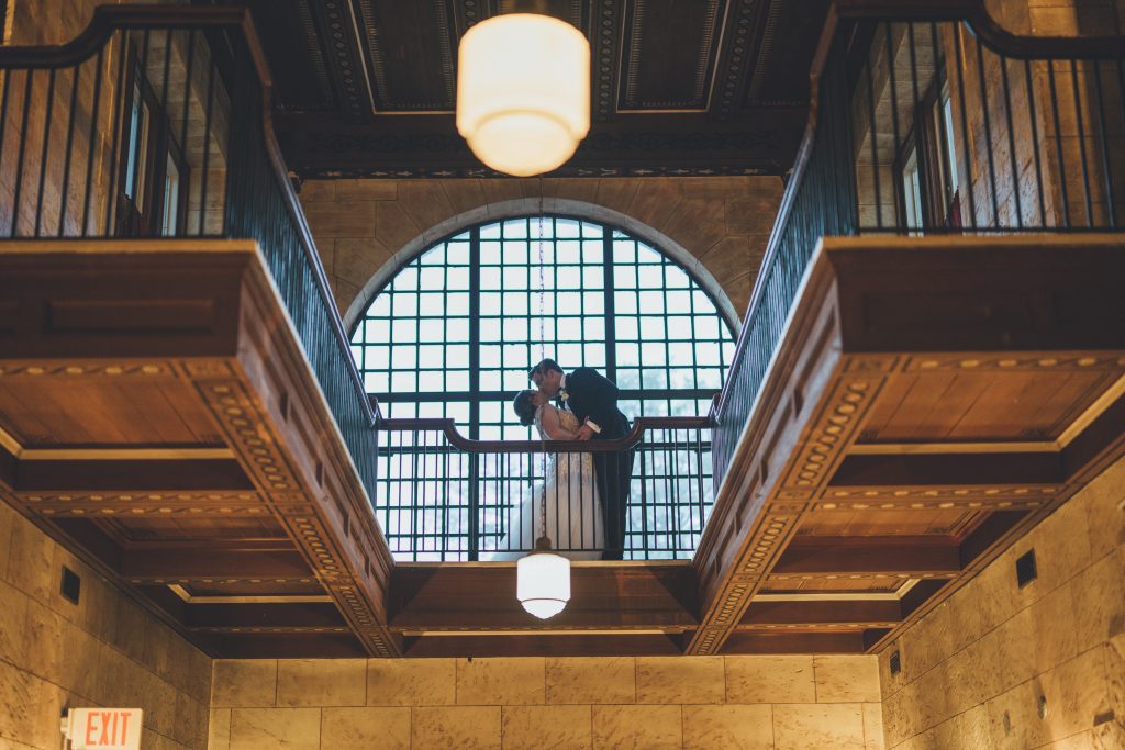 Bride and groom kissing on Grand Foyer Balcony at Treasury on the Plaza
