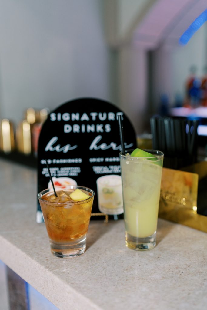 Two cocktails next to signature drink signage at Vault Bar