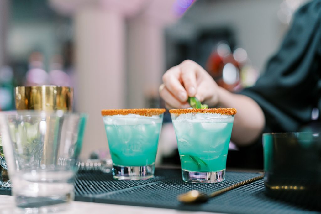 bartender garnishing blue margaritas