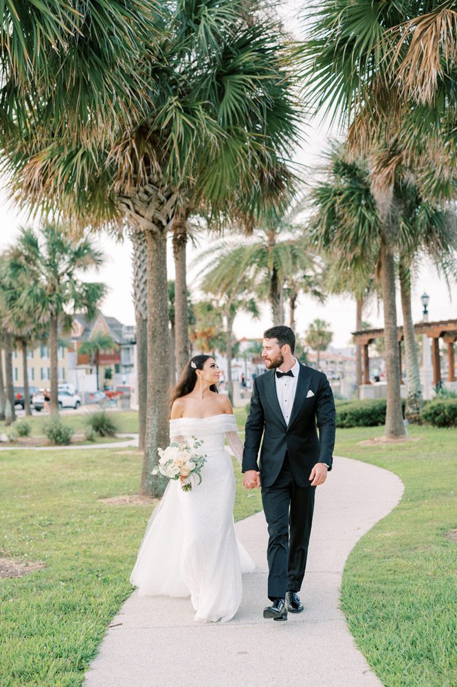 Bride and groom walk through downtown St. Augustine in front of The Treasury building