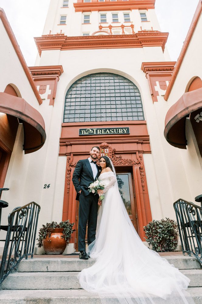 Bride and groom walk through downtown St. Augustine in front of The Treasury building