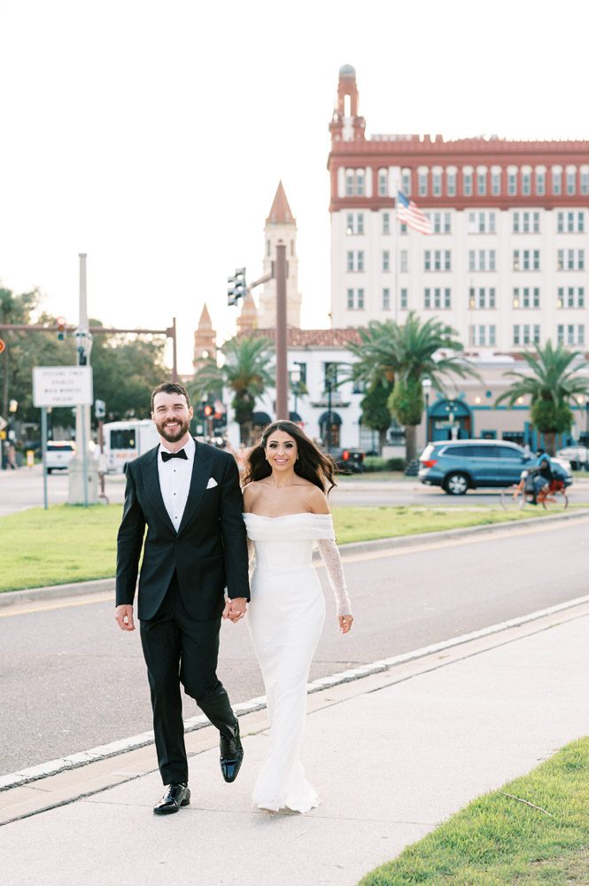 bride and groom walk through downtown St. Augustine in front of The Treasury building
