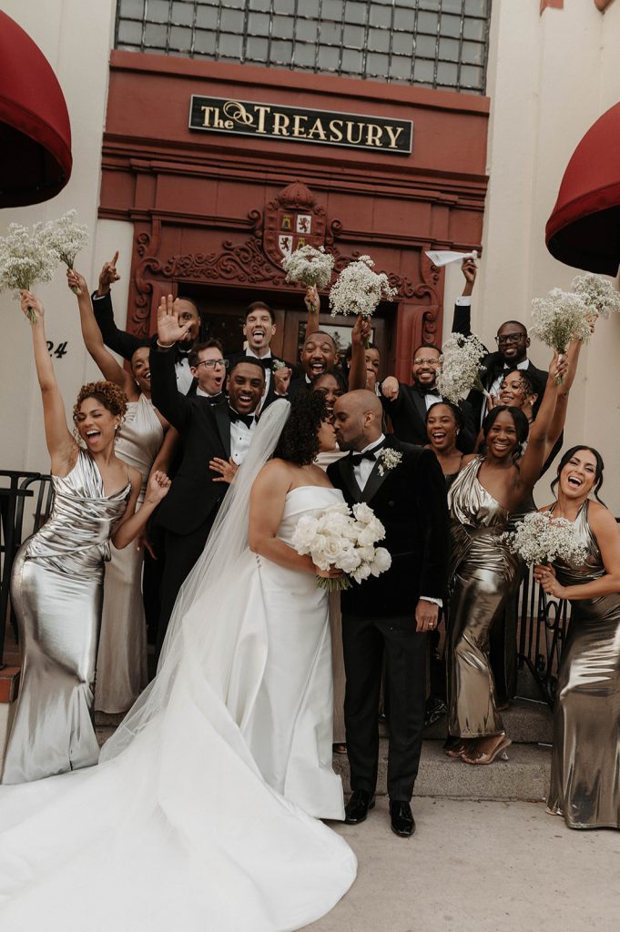 Ariel and James share a kiss with their wedding party in front of The Treasury on the Plaza. | Photo: Spencer Luca Photo