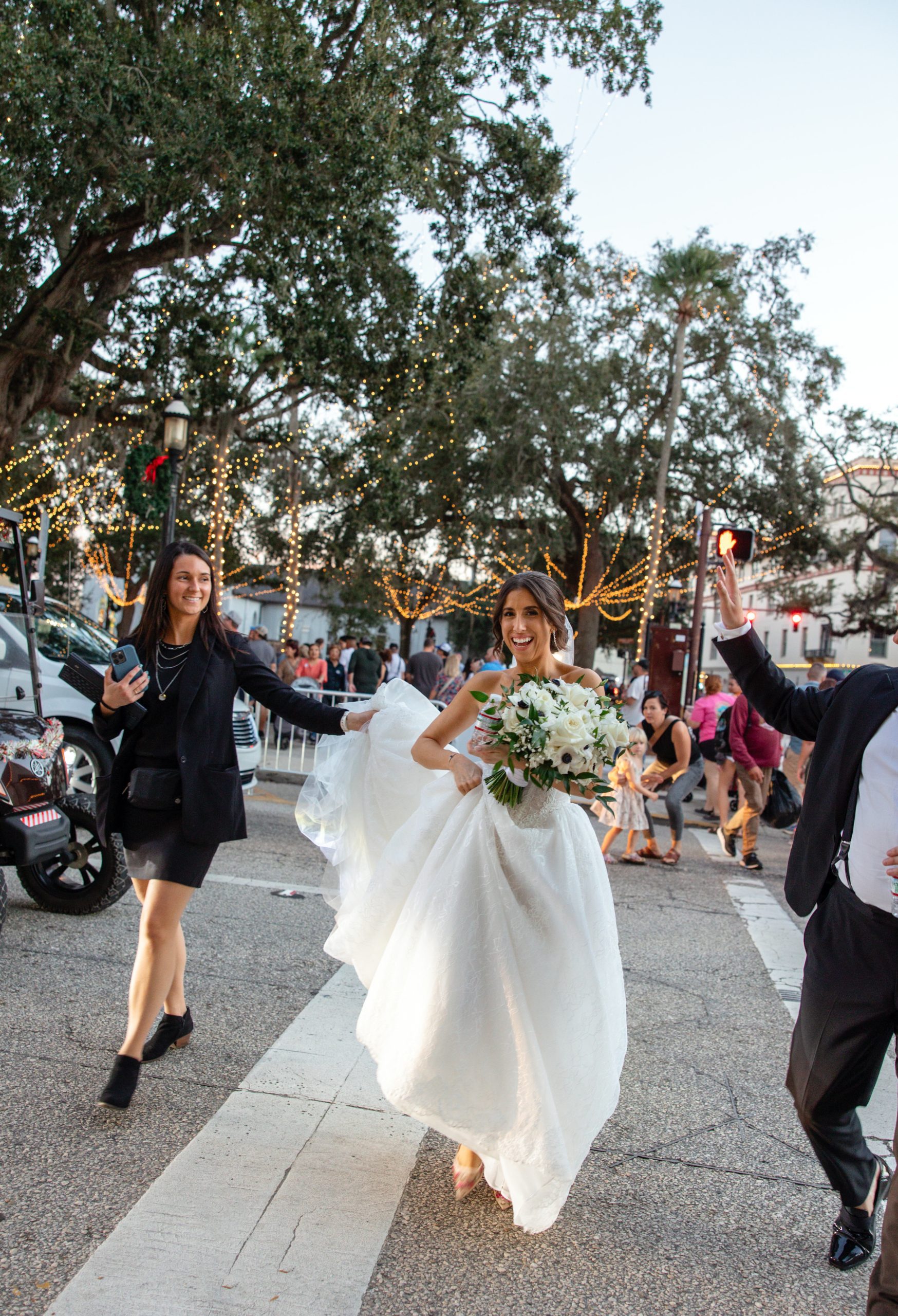 Wedding planner Lucy from Coastal Celebrations helps the bride with her dress while taking portraits around St. Augustine. | Photo: Danielle Teresa Photo