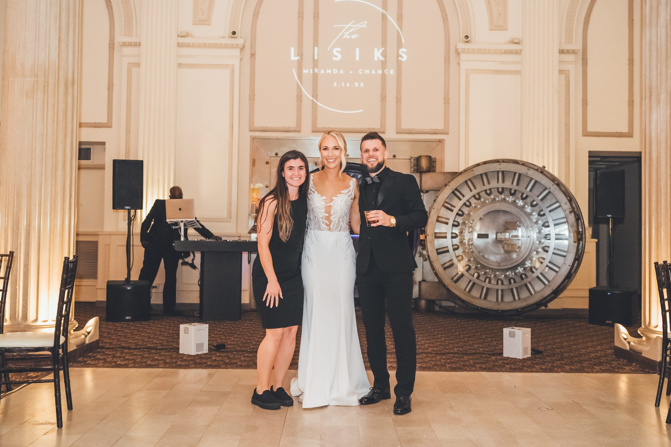 Wedding planner Emma from Coastal Celebrations takes a photo with her couple in front of the Vault Door in the Grand Ballroom of The Treasury on the Plaza. | Photo: Southern Palms Studio