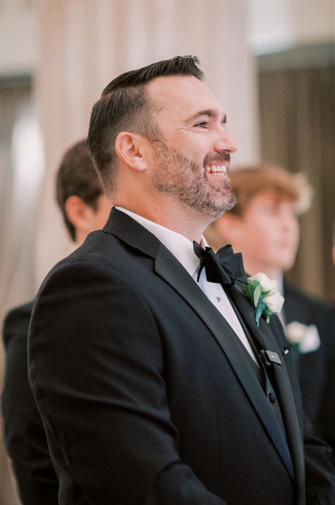 Groom smiling at bride walking down the aisle