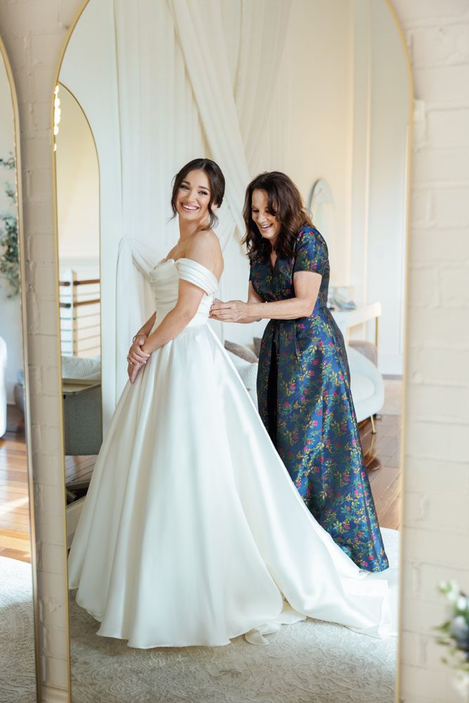 Mother putting daughter in her wedding dress