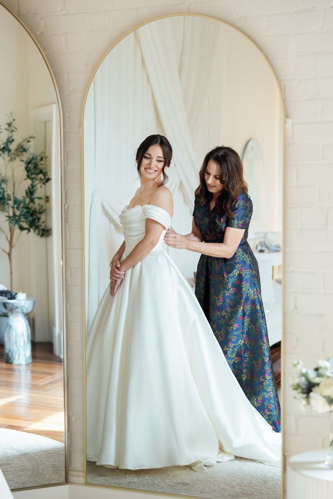 Mother putting daughter in her wedding dress