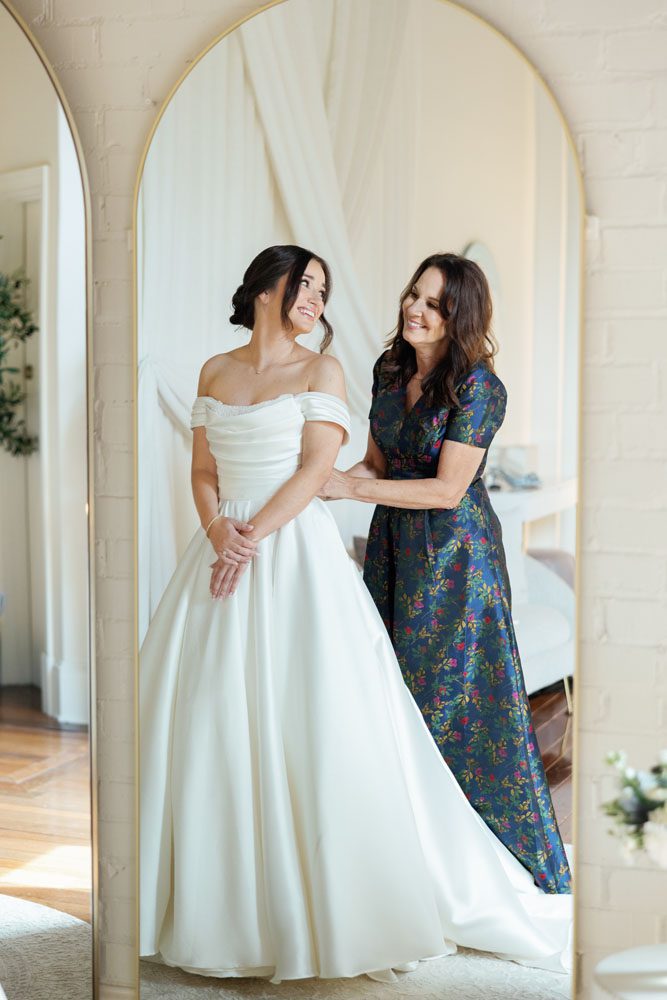 Mother putting daughter in her wedding dress