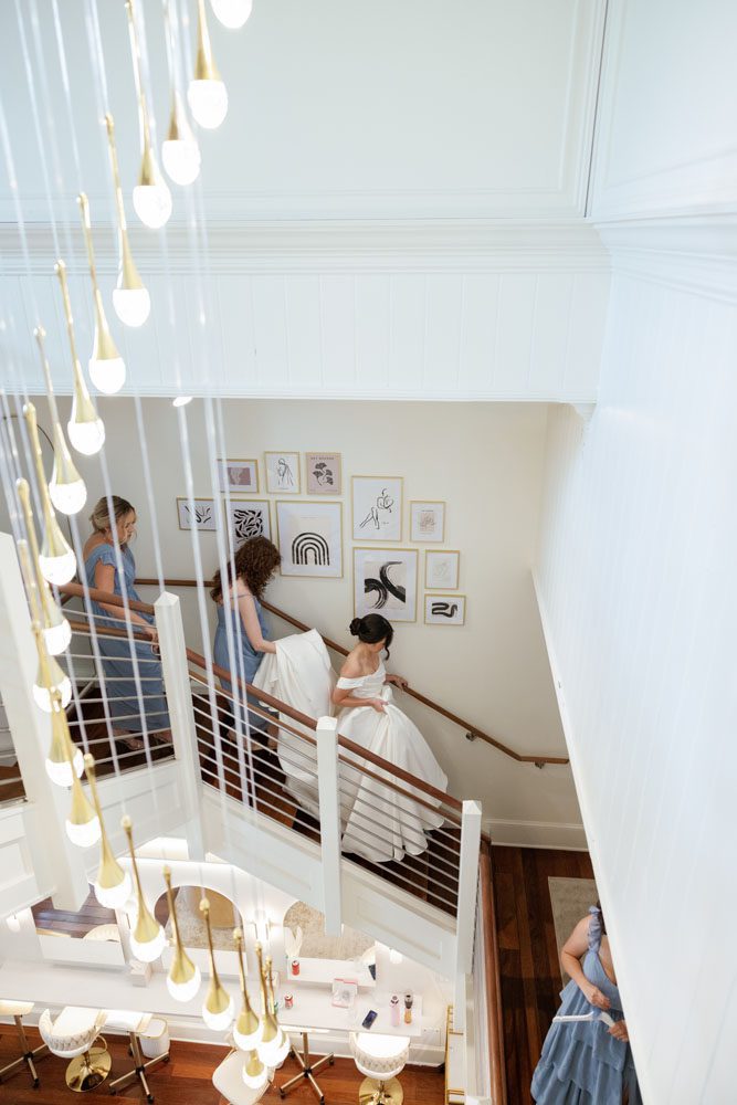 Bridesmaids helping Bride down the stairs